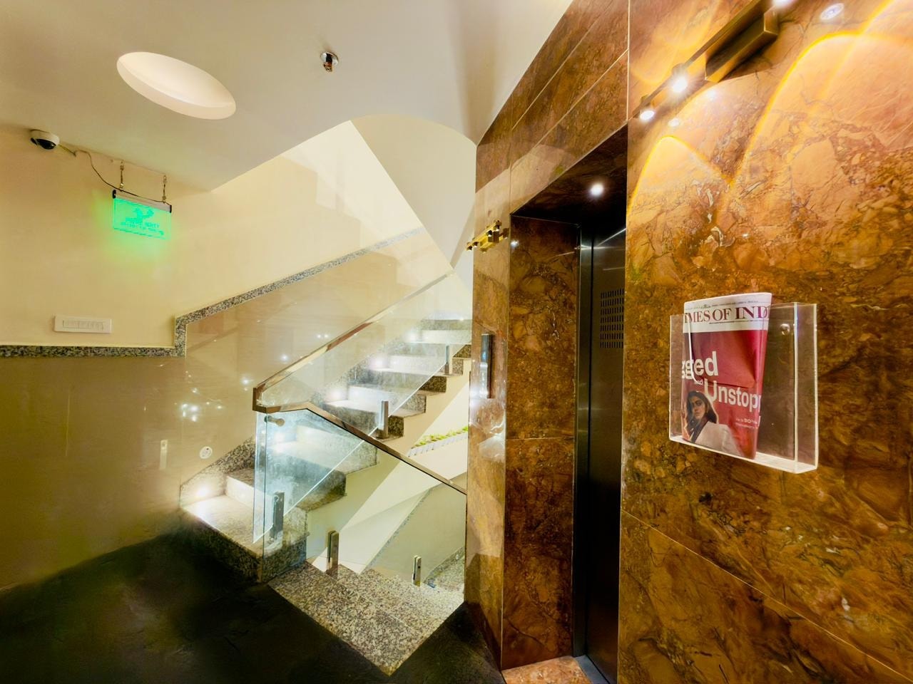 The lift lobby at Hotel Vagmi - marble walls, the lit granite staircase, the morning paper in its rack.